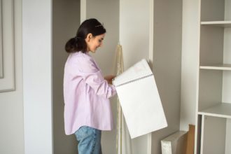 A cute girl is standing with a design project near an unassembled cabinet